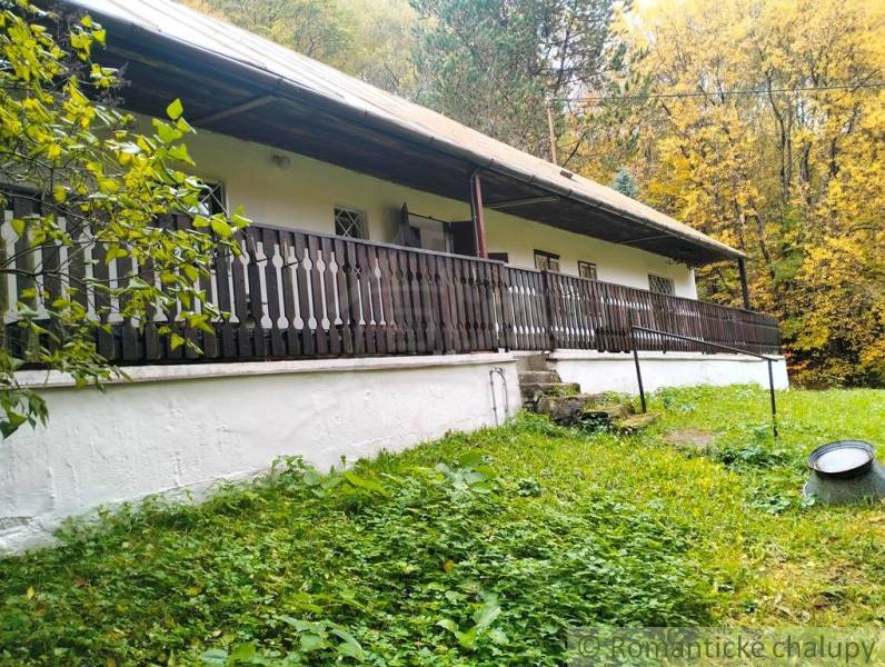 A cottage surrounded by greenery in Chocholná-Velčice, with wooden veranda railings.