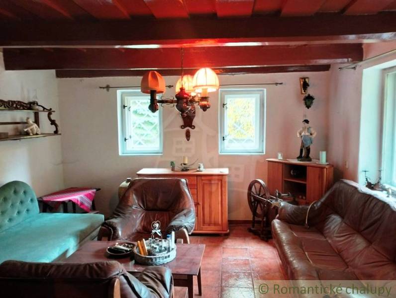An old cottage with leather furniture, a wooden ceiling, and a tavern chandelier.