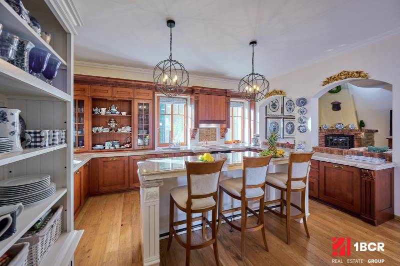 A kitchen in a villa with a wood-patterned floor, wooden cabinets, and an island with stools.