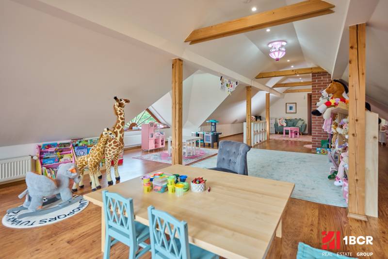 Children's playroom in a villa with a wooden decor floor, lots of toys, and a table for creativity.