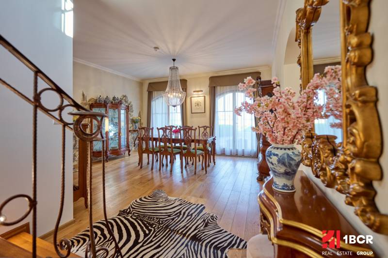 Interior of a villa with elegant furniture, a chandelier, and a wooden decor floor.