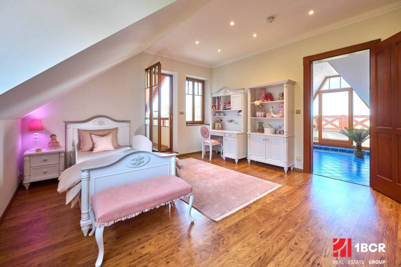 Children's room in a villa with white furniture, pink accessories, and a floor with a wooden decor.