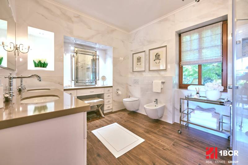 A bathroom in a villa with a wooden decor floor and marble walls.