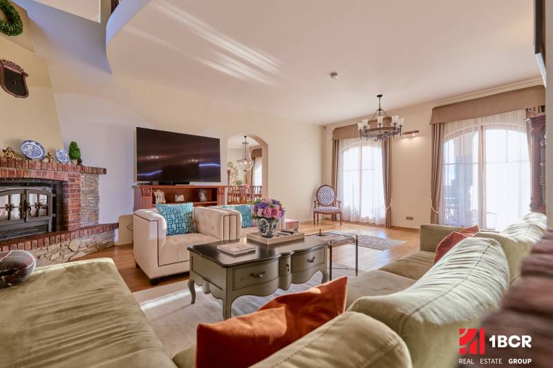 A spacious living room in the villa with comfortable seating, a television, and a tiled stove.