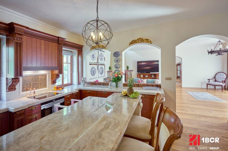 A kitchen in a villa with a marble island, decorative plates, and fruit.