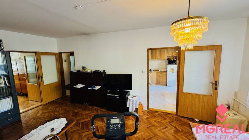 Living room with wood-patterned flooring, view of the kitchen in a 3-room apartment.