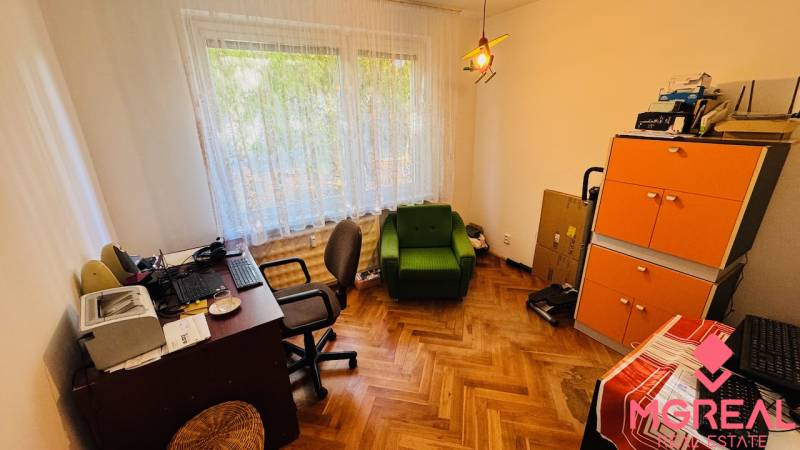 Office in a 3-room apartment with a wood-patterned floor, green chair, and cabinets.
