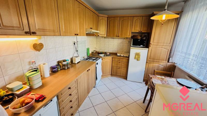 A kitchen in a 3-room apartment with a wooden decor floor and a corner unit.