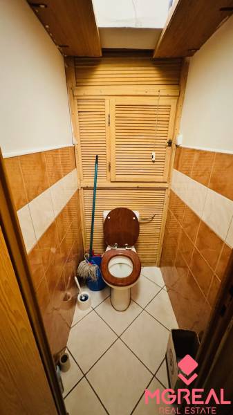 A toilet with ceramic tiles and a toilet brush in a 3-room apartment.