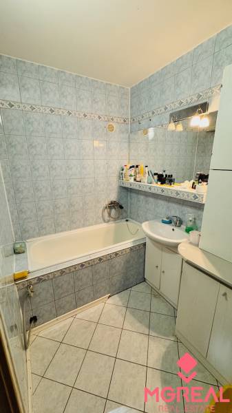 A bathroom with light tiles and a bathtub in a 3-room apartment.