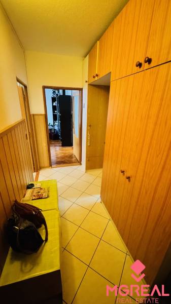 A hallway with tiles and wooden cabinets in a 3-room apartment.