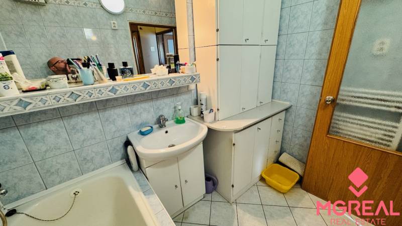 A bathroom in a 3-room apartment with a sink, cabinets, and a mirror.