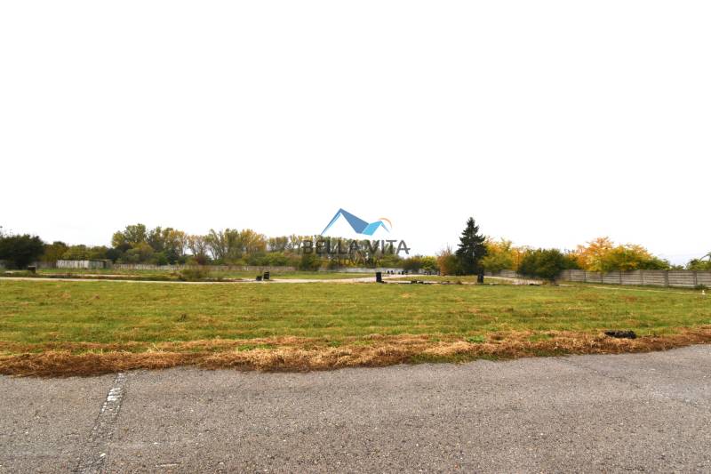 A grassy commercial plot on Nebojsa Street in Galanta with surrounding trees.