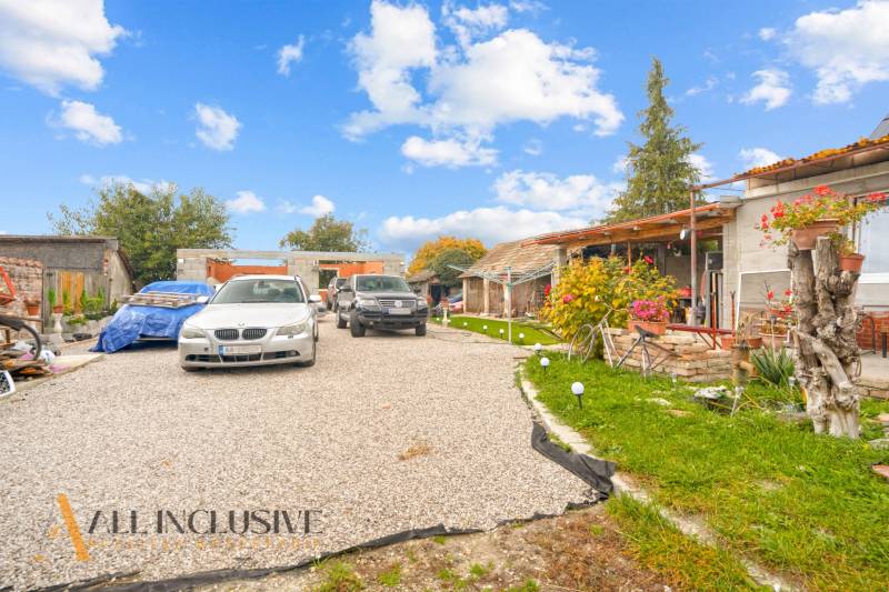 A family house in Dolné Saliby, with cars parked in front of the house and a well-maintained garden.