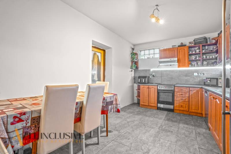 A kitchen in a family house with a dining table and a wooden kitchen unit.
