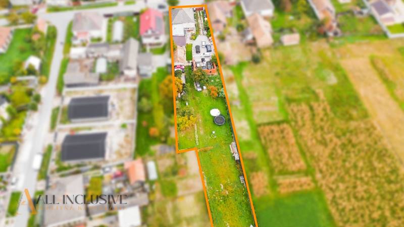 A top-down view of a family house and garden in Dolné Saliby, bordered by plots of land.