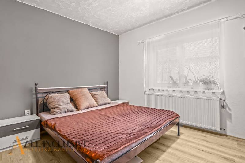Cozy bedroom with a metal bed and wood-patterned flooring in a family house.