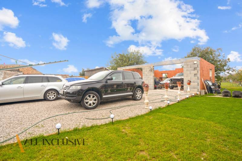 Parking in front of an unfinished family house in Dolné Saliby, trimmed lawn and vehicles.