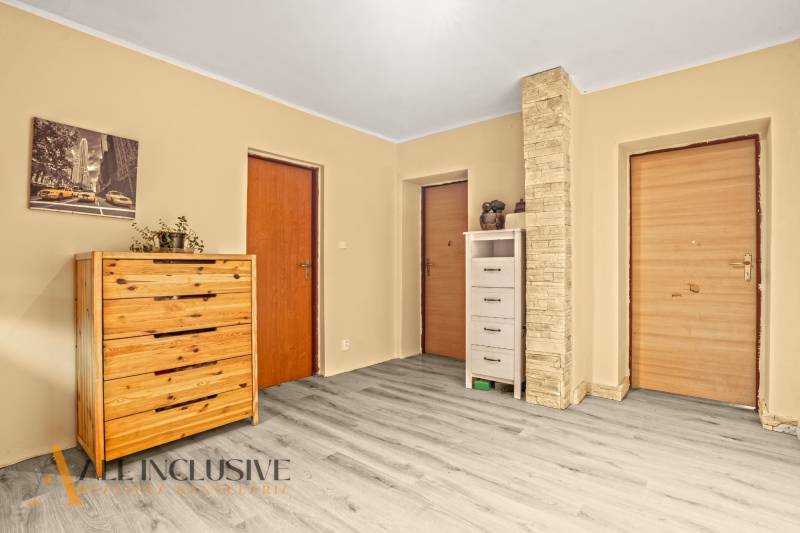 Interior of a family house with a wooden decor floor, a dresser, and two doors.