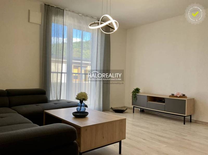 Living room in a three-room apartment with a sofa, table, and floor with a wooden decor.