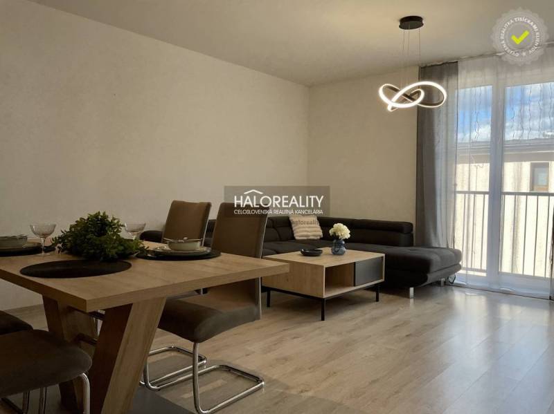 Living room with wood-patterned flooring and a comfortable sofa in a three-room apartment.