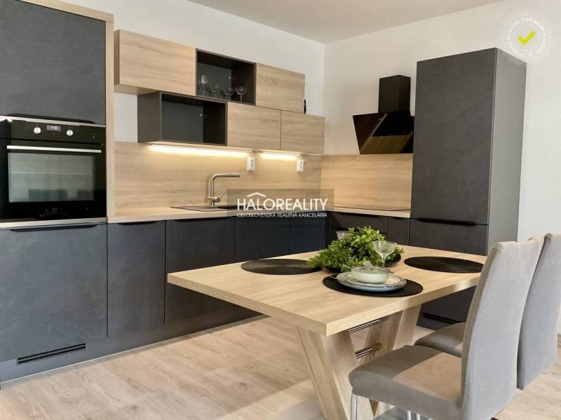 A kitchen in a 3-room apartment with a wood-patterned floor, black cabinets, and wooden accessories.