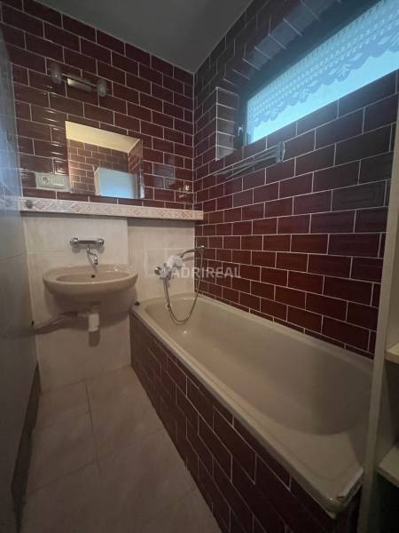 A bathroom in a family house with a bathtub, a sink, and red tiles.