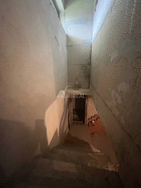 A staircase leading to the basement of a family house with exposed brickwork, without windows.