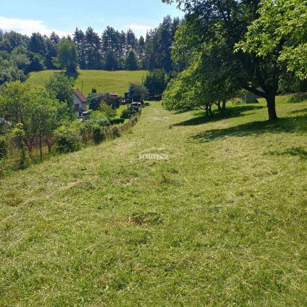 Recreational land in Žilina surrounded by greenery, trees, and a house in the background.