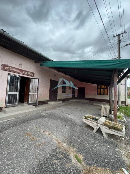 A family house in Plášťovce with a concrete courtyard and entrance door under a canopy.