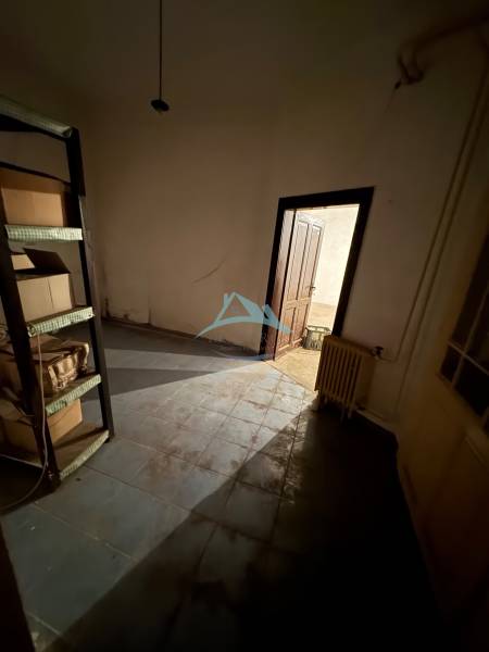 A dark room with a shelf, a door, and a radiator in a family house.