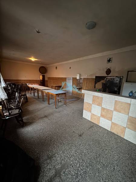 Room with long tables in a family house, with simple lighting and tiles on the wall.