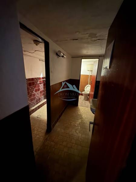A dark hallway with tiles and a toilet in a family house.