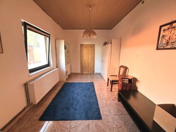 Room with tiles, carpet, furniture, and a large window in a family house.