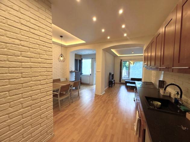 A family house with white brick walls, a wooden decor floor, and a dining table.