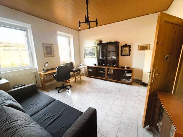 Living room with an office desk, sofa, and glass cabinet in a family house.