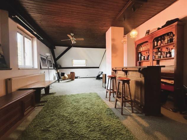 Family house with a wooden decor floor, a bar, and a green carpet.