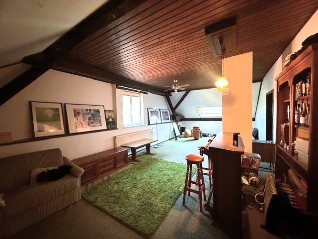 Attic living room of a family house with carpet and wooden ceiling.