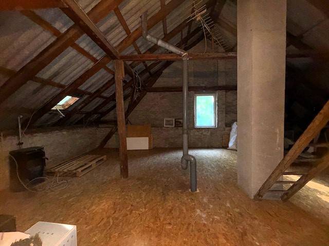 Attic in a family house with wooden beams and a chimney, floor with wooden decor.