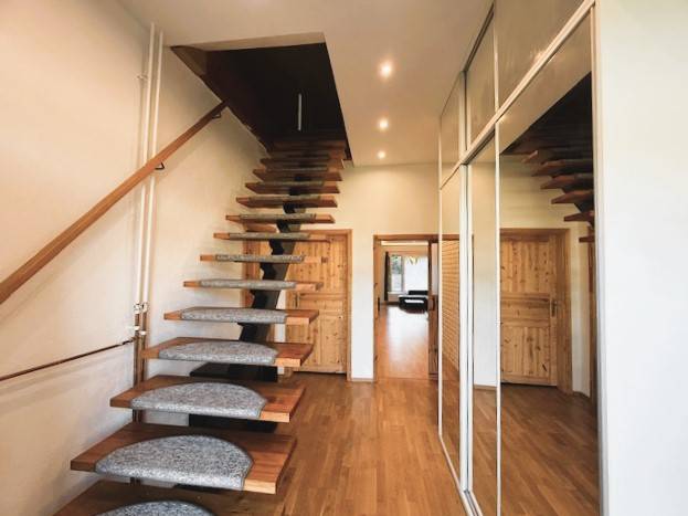 A staircase with a wooden decor floor and a mirrored wall in a family house.