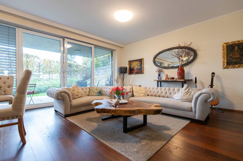 Living room in a three-room apartment with a wood-patterned floor and a large window.