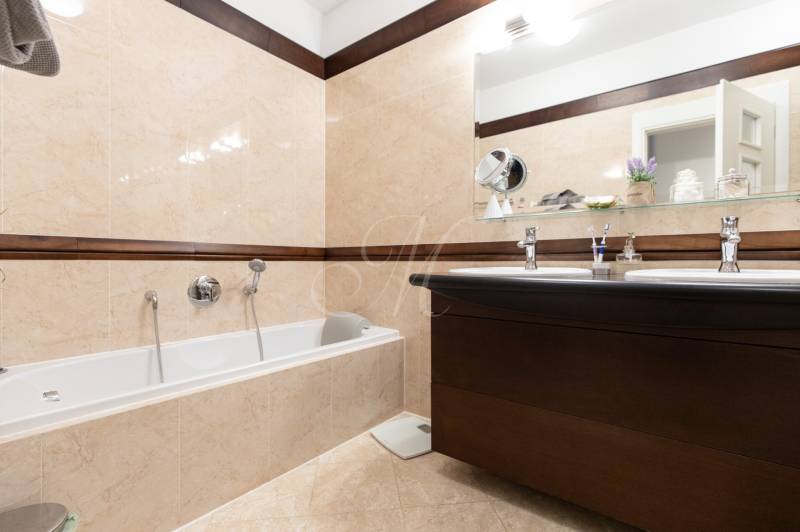 A bathroom with a bathtub and two sinks in a 3-room apartment, beige tiles.