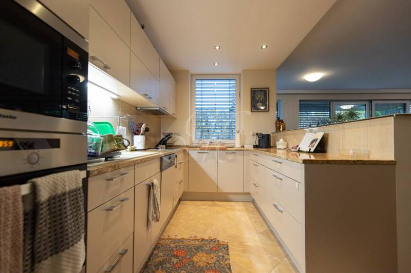 A kitchen in a 3-room apartment with white cabinets, tiles, and appliances.