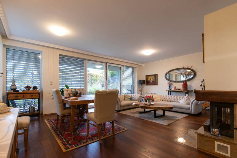 Living room in a three-room apartment with a wood-patterned floor and comfortable seating.