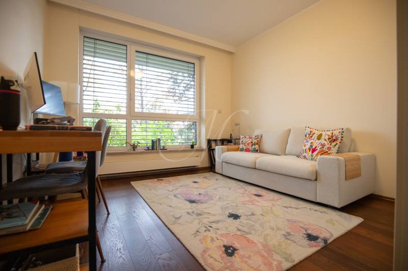 A room in a 3-room apartment with a carpet, a sofa, and a floor with a wooden decor.