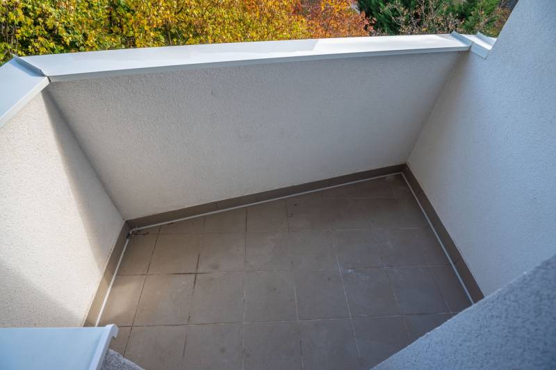 A balcony with tiles and a view of autumn nature in a 3-room apartment.