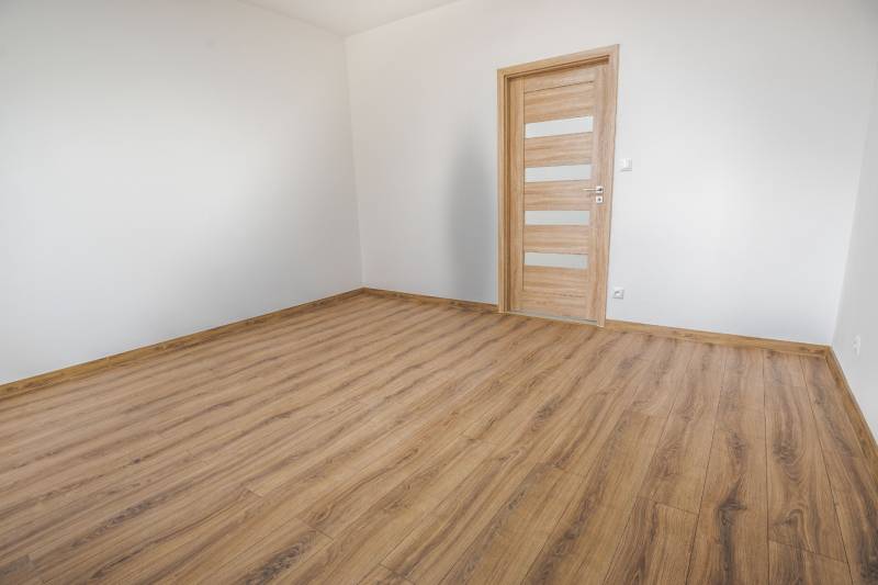 A room with white walls and a floor with a wooden decor in a 3-room apartment.