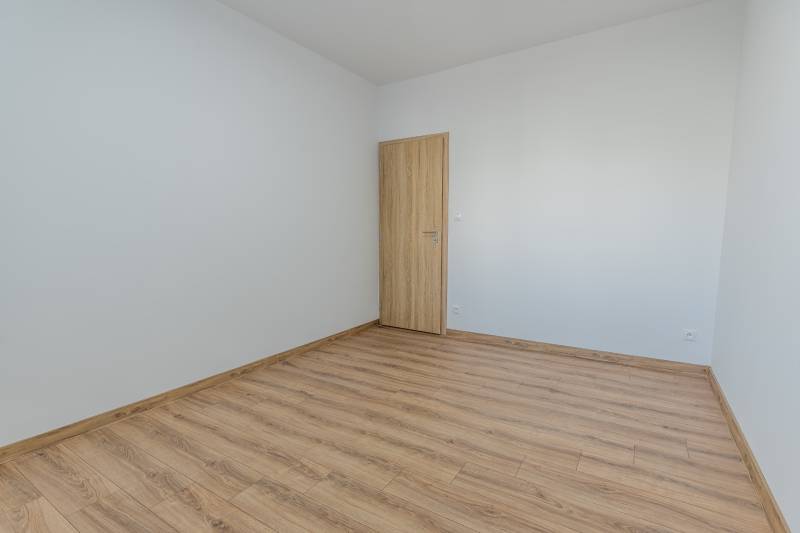 Empty room with white walls and a floor with a wood decor, 3-room apartment.