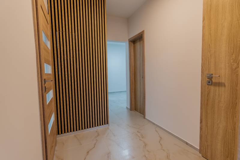 A hallway in a 3-room apartment with wooden doors and a decorative wall.