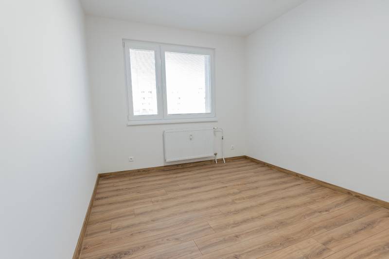 A room with white walls, a window, and a floor with a wood decor in a 3-room apartment.